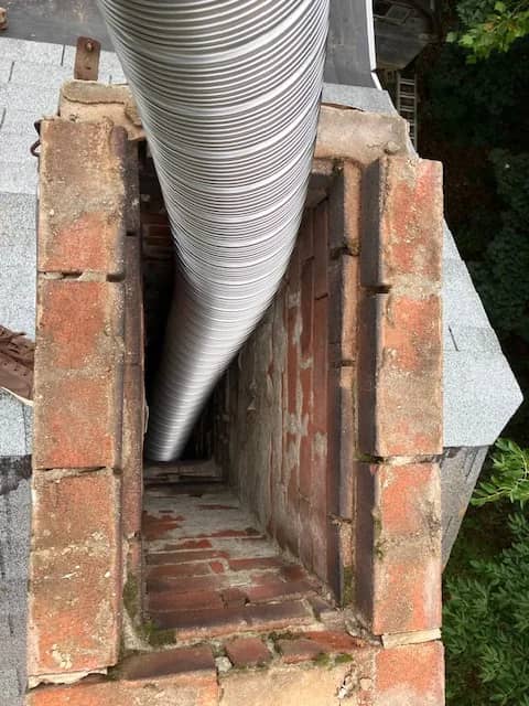 Stainless steel liner running down the inside of an open brick chimney.